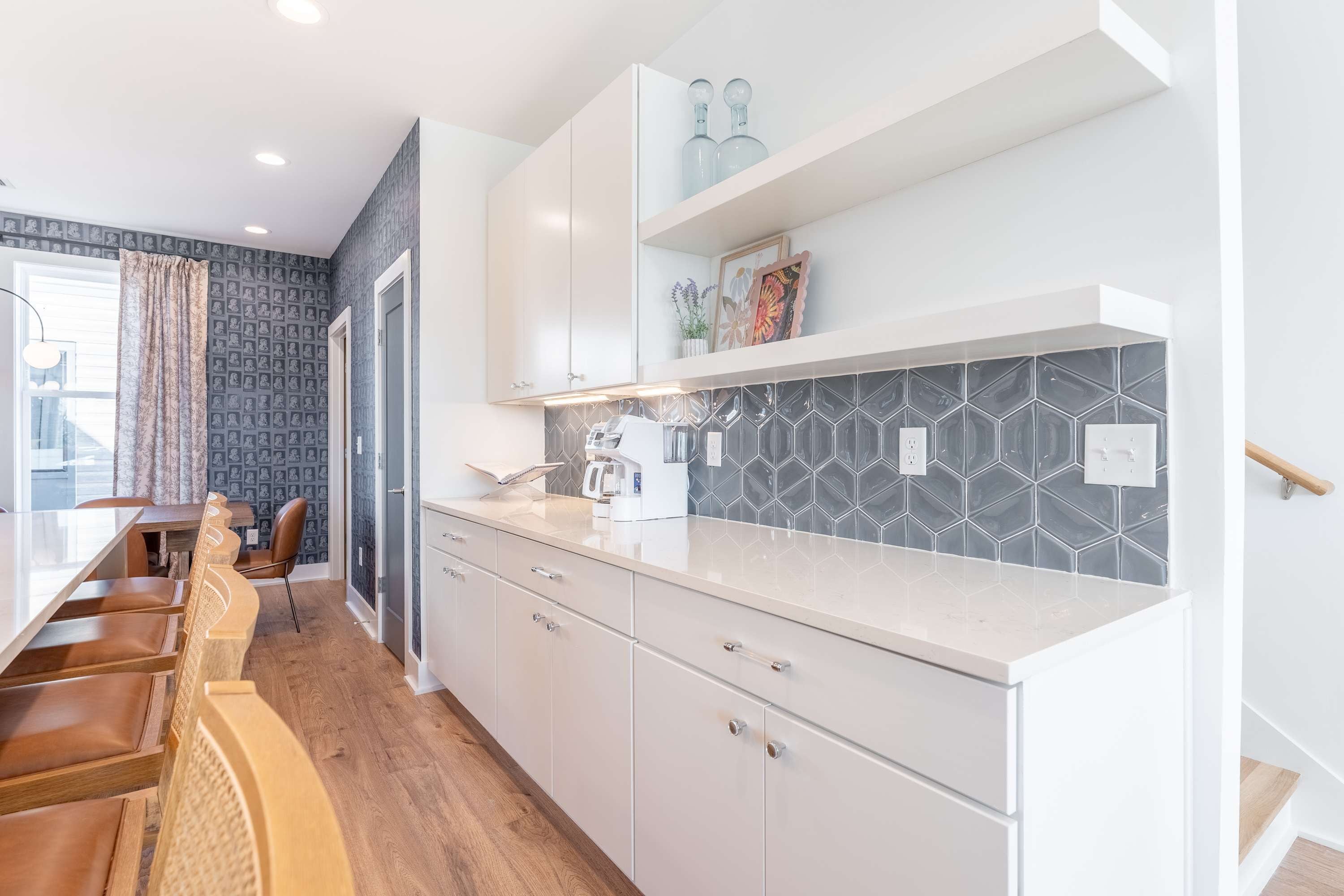 Una cocina moderna con armarios blancos, encimera de mármol y salpicadero de azulejos hexagonales.