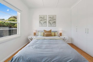 A bedroom with a bed, bedside tables, a wardrobe, and two wall-mounted artworks. - St Pauls Haven - 3brm Charming Cottage in Sorrento (Sorrento)