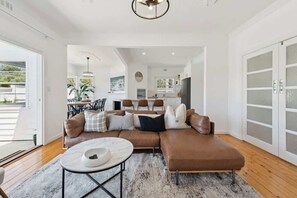 A modern living room with a sectional sofa, a coffee table, and a dining area in the background. - St Pauls Haven - 3brm Charming Cottage in Sorrento (Sorrento)