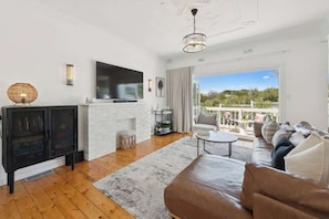 Una sala moderna con chimenea, televisor de pantalla plana, sofá de cuero y balcón con vistas.
