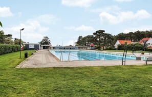Una piscina con separadores de carriles, una zona de estar cubierta y un edificio con la inscripción 'MALENBÆDET' al fondo.