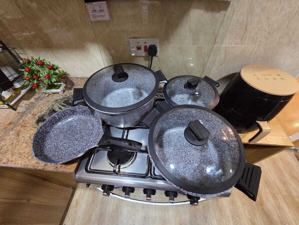 Una cucina con piano cottura a gas, tre pentole coperte, una piccola pianta in vaso e una macchina per il caffè.