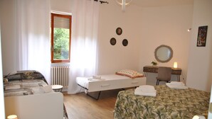 Un dormitorio con cama, mesa de masajes, una silla y una mesita de noche con lámpara.