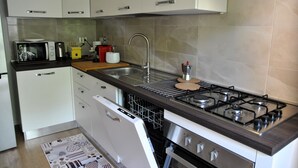Una cocina moderna con armarios blancos, estufa de acero inoxidable y lavavajillas.