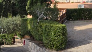 A paved pathway leading to a building with a stone wall and a red mailbox.