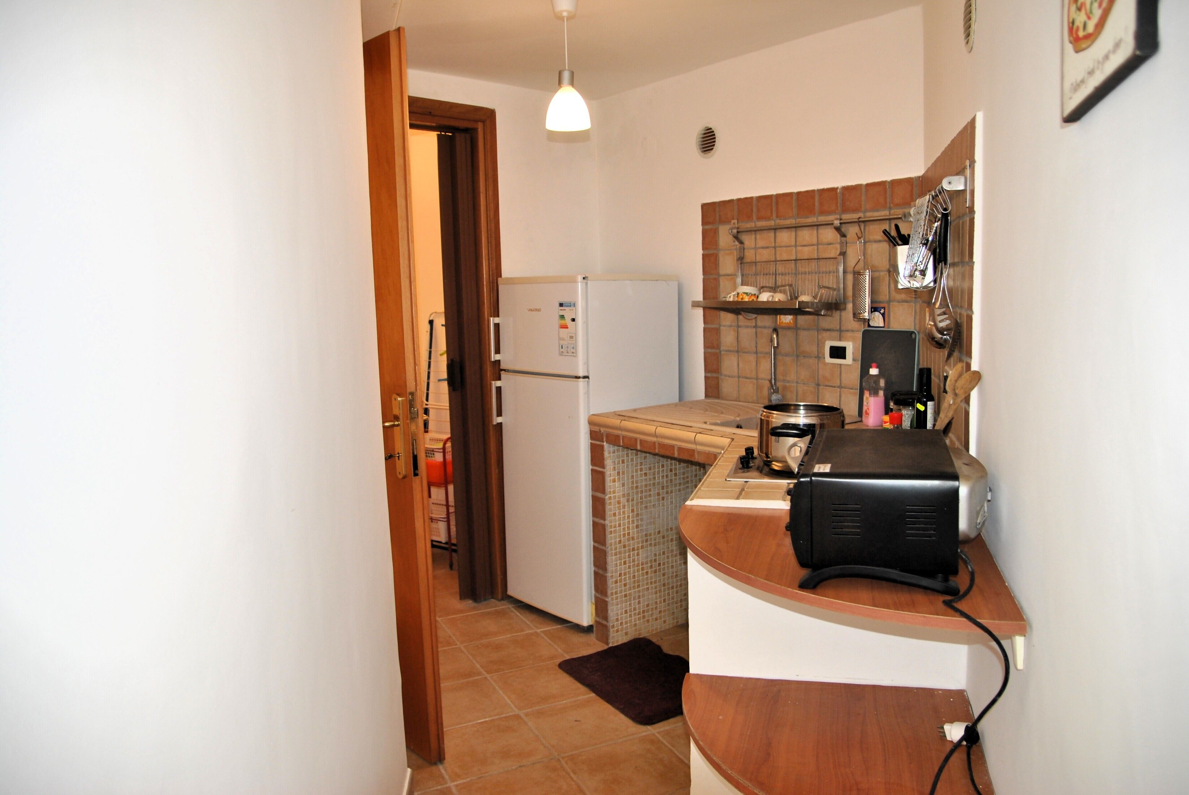 Eine kleine Küche mit Kühlschrank, Toaster und gefliestem Spritzschutz.