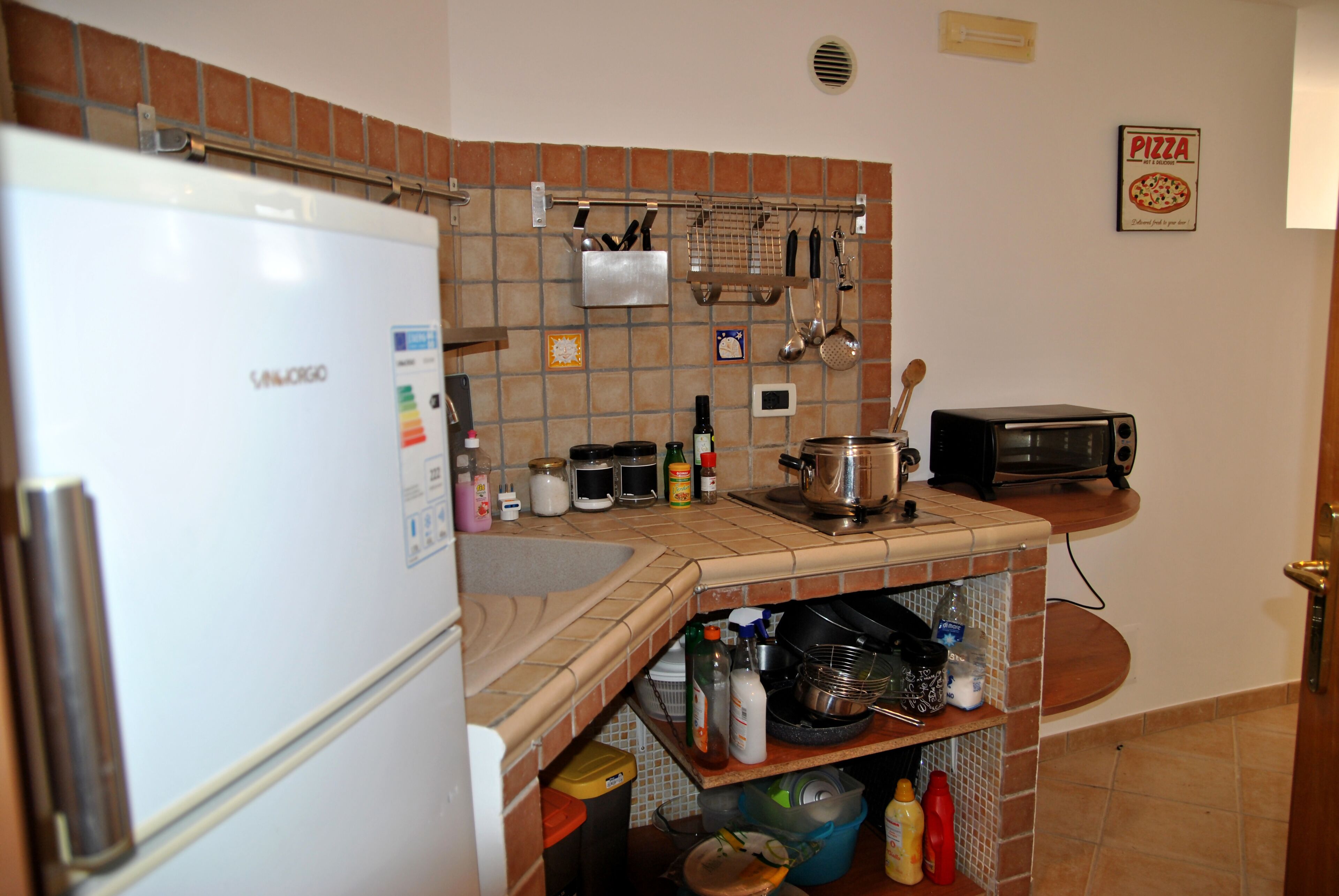 A kitchen with a refrigerator, stove, sink, and various kitchen utensils.
