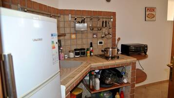 A kitchen with a refrigerator, stove, sink, and various kitchen utensils.