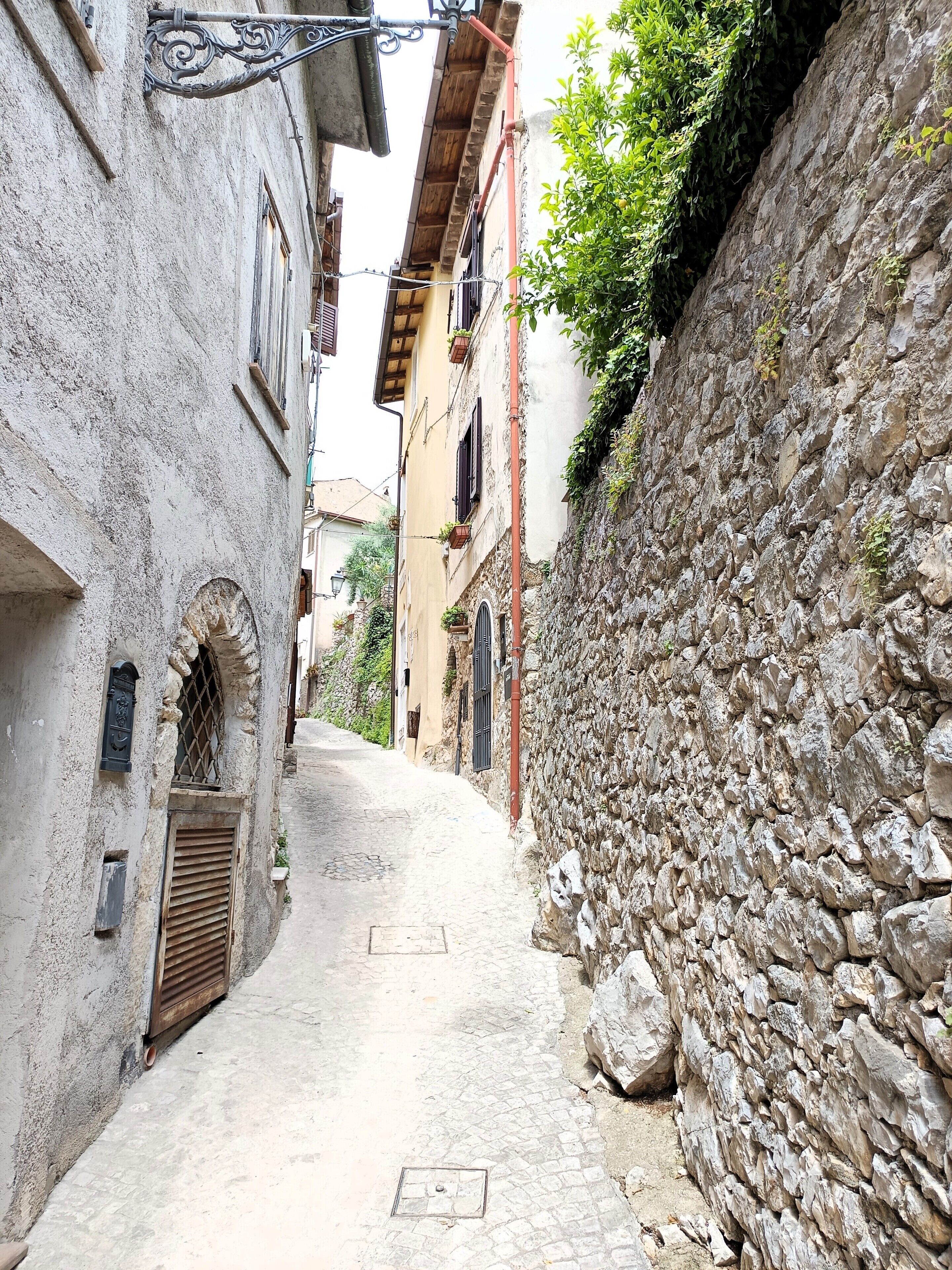 Una estrecha calle adoquinada flanqueada por edificios históricos de piedra con arcos y contraventanas de madera.