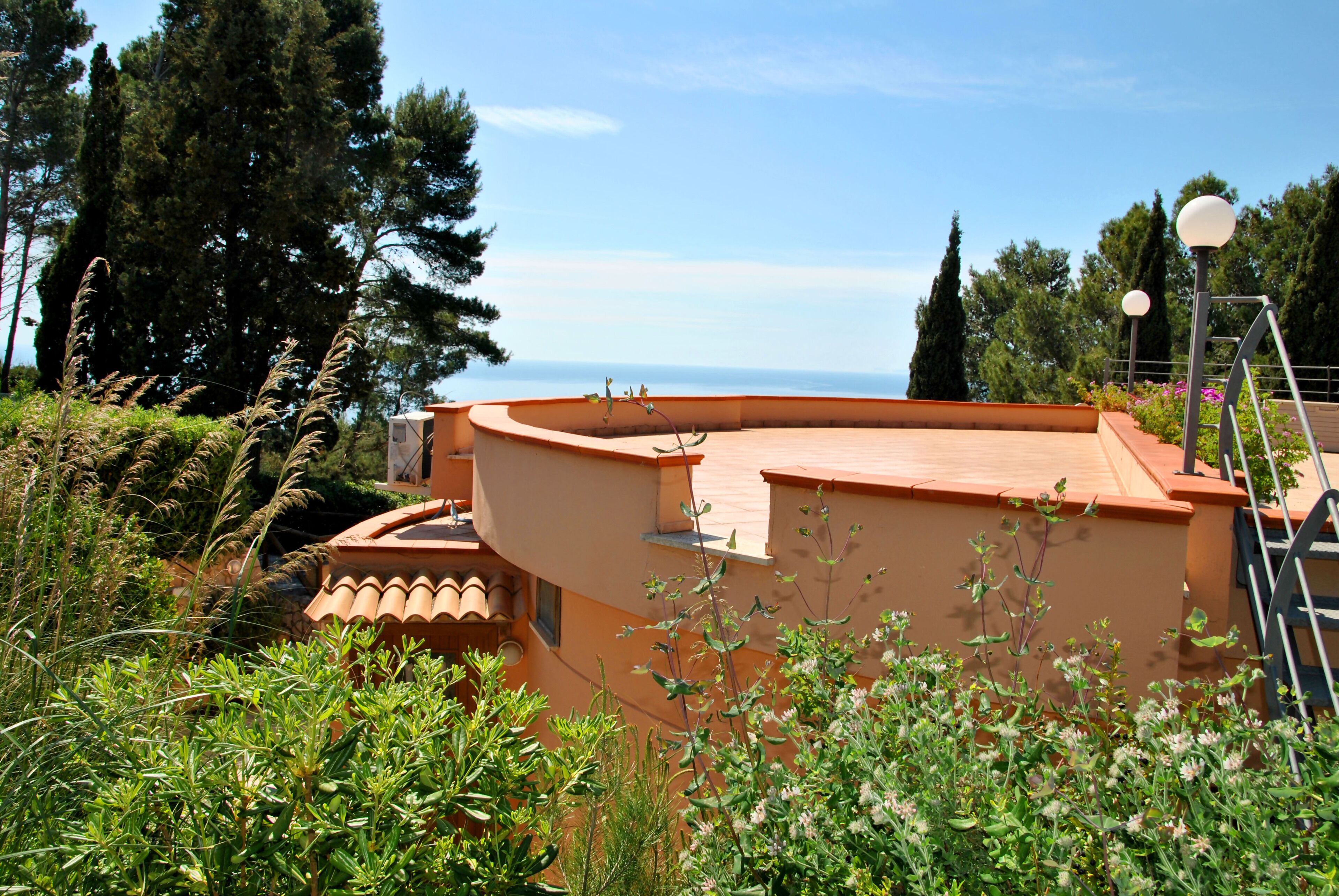 A building with a curved roof, surrounded by greenery and trees.