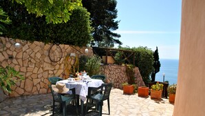 An outdoor patio with a stone wall, a table set for dining, and potted plants. - Casa Simon Nature and Sea (Sperlonga)