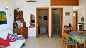 A cozy living room with a sofa, wooden cabinet, and a dining area with a table and chairs. - Casa Simon Nature and Sea (Sperlonga)