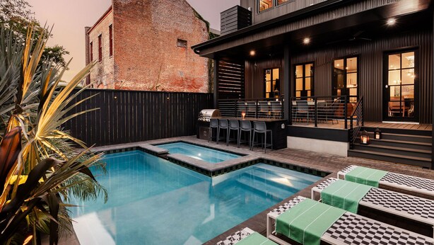 Un'area piscina moderna con un angolo barbecue e poltrona relax.