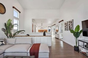 A spacious living area with a sofa, a coffee table, and a large plant. There is a kitchen area in the background with a dining table and chairs. - LGD Luxury Combo | Heated Pool & Hot Tub (New Orleans)