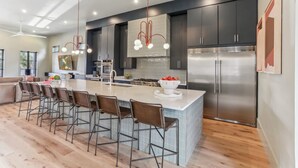 Una cucina moderna con una grande isola, mobili scuri, elettrodomestici in acciaio inossidabile e una lampada a sospensione.