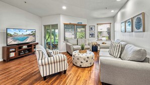 A living room with a flat-screen TV, striped armchairs, a grey sofa, and a coffee table with a decorative basket. - Bayside Endless Summer | Walk to Siesta Key Beach, Community Pool, & Tennis Court (Siesta Key)
