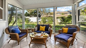 A sunroom with wicker furniture, large windows, and a ceiling fan. - Bayside Endless Summer | Walk to Siesta Key Beach, Community Pool, & Tennis Court (Siesta Key)
