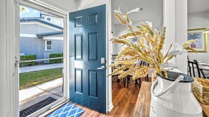 A modern home interior with a blue door, a dining area with a wooden table, and a white vase with flowers. - Bayside Endless Summer | Walk to Siesta Key Beach, Community Pool, & Tennis Court (Siesta Key)