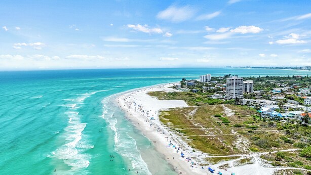 A coastal view with a beach, ocean, and buildings. - Bayside Endless Summer | Walk to Siesta Key Beach, Community Pool, & Tennis Court (Siesta Key)