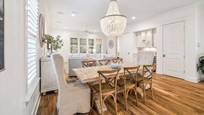 A dining area with a wooden table and chairs, a chandelier, and a white ceiling fan. - Watersound~ Golf Cart | Bikes | Gated Community | Private Beach Access (Santa Rosa Beach)