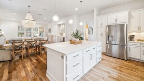 A spacious kitchen with white cabinetry, a large island, and a stainless steel refrigerator. - Watersound~ Golf Cart | Bikes | Gated Community | Private Beach Access (Santa Rosa Beach)