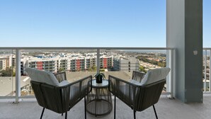 A balcony with two wicker chairs and a small table, overlooking a cityscape with multi-story buildings. - Blue Horizon' 3BD 2BA Full Ocean Views Panoramic Heaven Venice Beach (Marina del Rey)