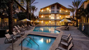 A pool area with lounge chairs and umbrellas, surrounded by palm trees and a multi-story building with balconies. - Blue Horizon' 3BD 2BA Full Ocean Views Panoramic Heaven Venice Beach (Marina del Rey)