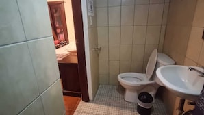 A small bathroom with a toilet, sink, and tiled floor. - Hotel Ciudad de los sueños (Antigua Guatemala)