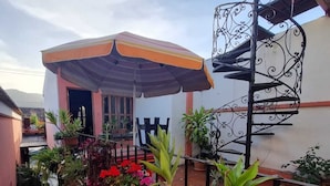 A covered outdoor area with a metal staircase, potted plants, and a building entrance. - Hotel Ciudad de los sueños (Antigua Guatemala)