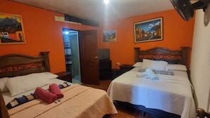 A room with two beds, a ceiling fan, and a door leading to another room. - Hotel Ciudad de los sueños (Antigua Guatemala)