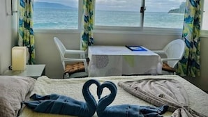 A hotel room with a bed, a desk, and a view of the sea. - Playa Blanca Beach Resort & Dive Centre (Puerto Galera)