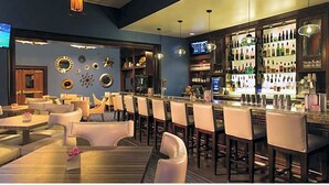 Een bar met verschillende zitplaatsen, een goed gevulde bar en decoratieve wandelementen.