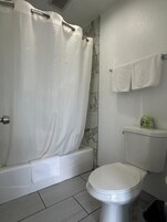 A bathroom with a shower curtain, a toilet, and a towel rack with towels.