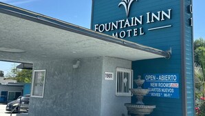 The exterior of Fountain Inn Motel with a blue facade, a sign indicating it is open, and a number '1901' on the wall.