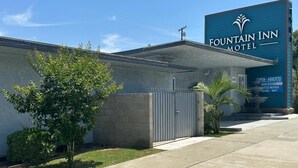 A Fountain Inn Motel with a large sign, a gated entrance, and a small tree in the foreground.