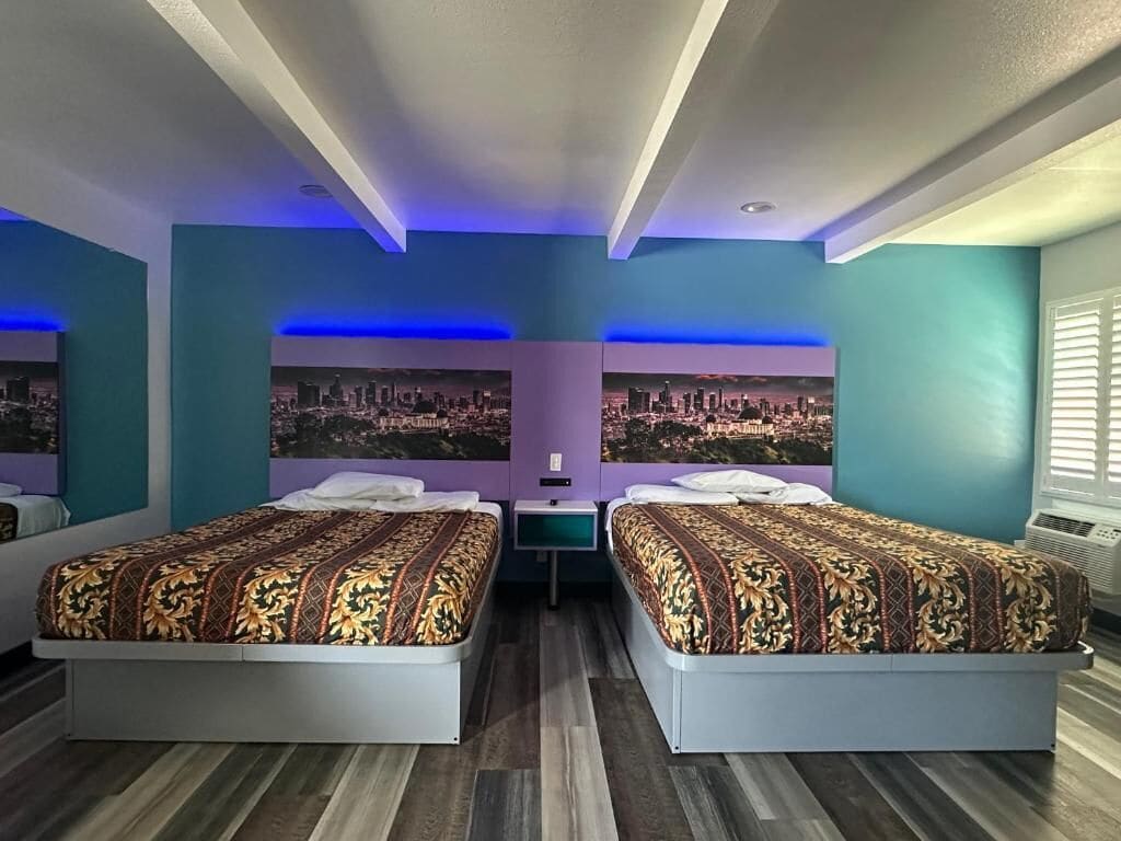 A hotel room with two beds, a cityscape view, and a modern design.
