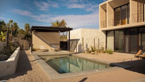 Un espace piscine moderne agrémenté d’une pergola, de chaises longues et offrant une vue dégagée sur le ciel.