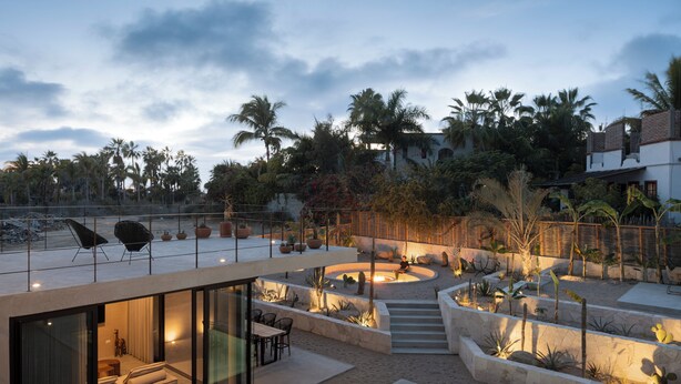 Un espace de vie extérieur moderne, doté d’une piscine, de coins salon et offrant une vue sur des palmiers.