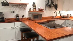 A kitchen with a wooden countertop, a double espresso machine, a microwave, a sink, and two bar stools. - Perfectly located Extra large 1-bedroom condo in central Aspen (Aspen)