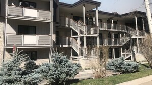 A multi-story residential building with balconies, staircases, and a landscaped garden with evergreen shrubs. - Perfectly located Extra large 1-bedroom condo in central Aspen (Aspen)