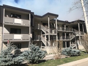 A multi-story residential building with balconies, staircases, and a landscaped garden with evergreen shrubs. - Perfectly located Extra large 1-bedroom condo in central Aspen (Aspen)