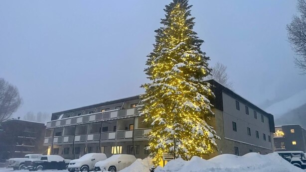 A snow-covered parking lot with a large Christmas tree adorned with lights. - Perfectly located Extra large 1-bedroom condo in central Aspen (Aspen)