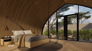 Un dormitorio con una cama grande, una mesita de noche y vistas al exterior a través de un ventanal amplio.