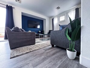 A modern living room with a grey sofa, a coffee table, and a large potted plant.