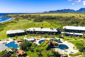 Ein Resort mit mehreren Gebäuden, einem großen Poolbereich und Blick auf den Ozean und die Berge.