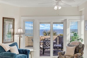 A room with a view of the sea, a ceiling fan, and two sofas. - Gorgeous Ocean Views with Prime South End Location | Heated Pool Access (Tybee Island)