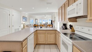 A modern kitchen with wooden cabinets, a built-in oven, and a microwave. - Gorgeous Ocean Views with Prime South End Location | Heated Pool Access (Tybee Island)