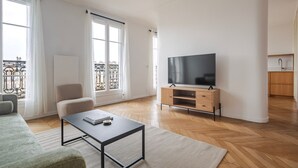 Un salon spacieux doté d’une grande télévision, d’un canapé, d’une table basse et d’un balcon agrémenté d’une balustrade.