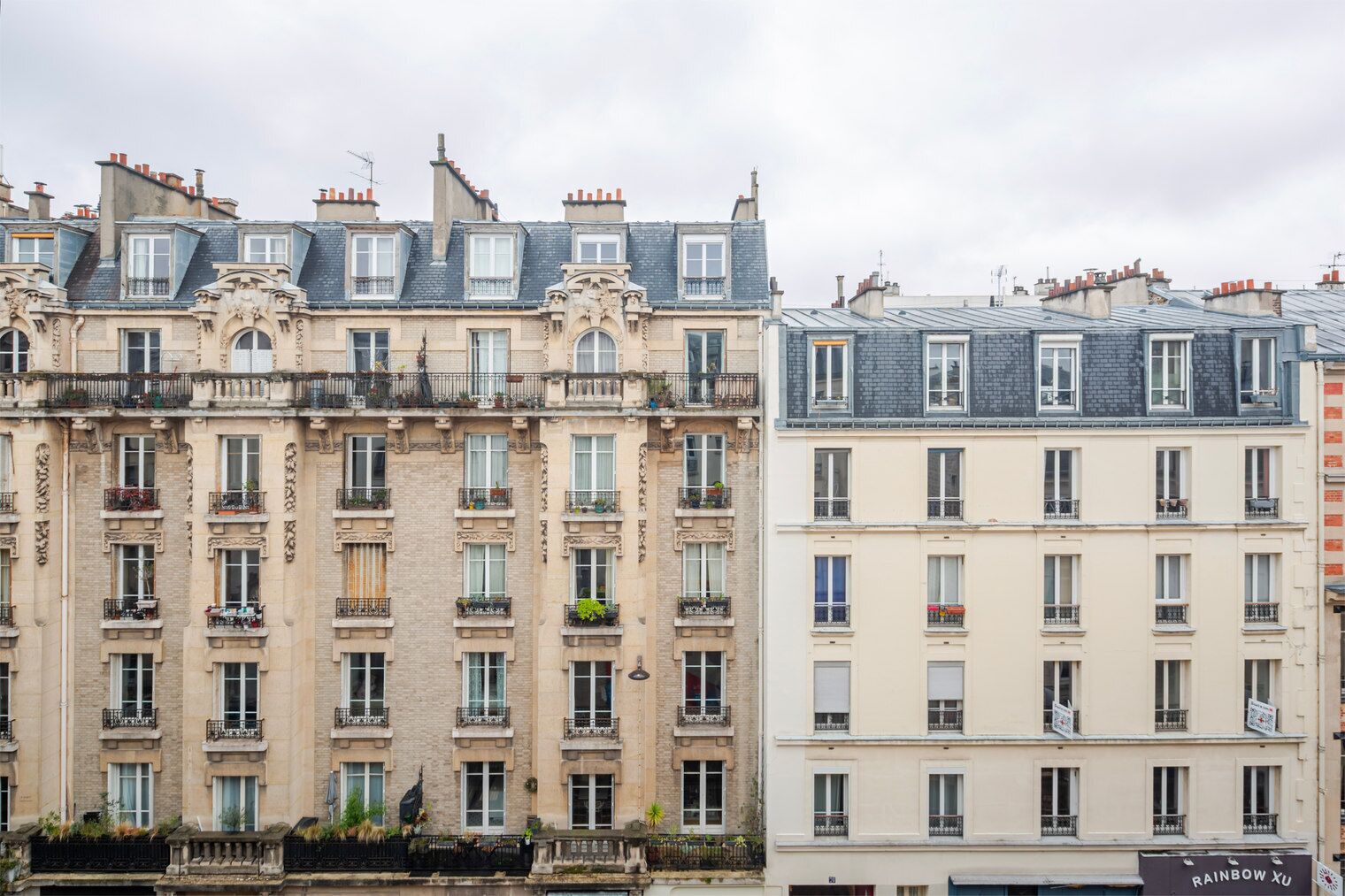 A row of multi-story buildings with uniform architectural style, featuring balconies and a consistent facade design.