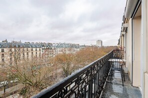 Un balcon offrant une vue sur le paysage urbain, avec des bâtiments et des arbres.